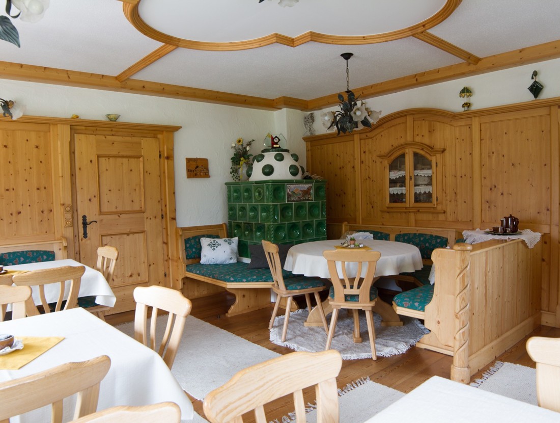 Gemütliche Stube mit Holzmöbeln und grünem Kachelofen, Tisch und Stühlen