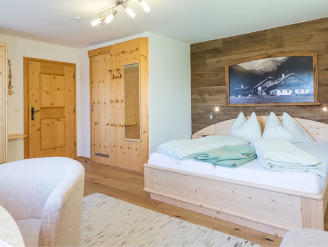 Gemütliches Schlafzimmer mit Holzmöbeln und großem Bild über dem Bett