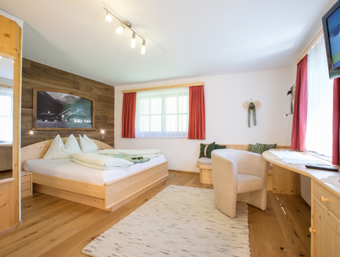 Helles Schlafzimmer mit Holzbett, Sofa und Tisch, modern dekoriert